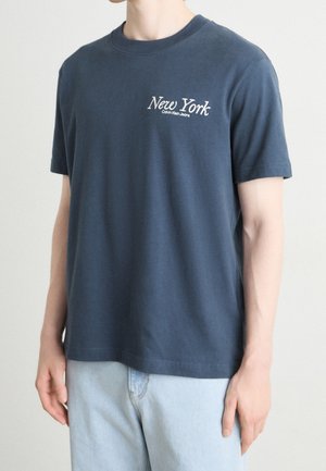 Granatowy bawełniany t-shirt z krótkimi rękawami, z białym napisem „New York” oraz logo „Calvin Klein Jeans” na lewej piersi.