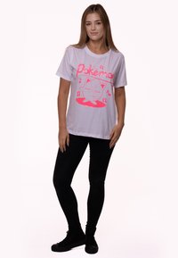 White cotton Pokémon t-shirt with pink graphic design featuring a character with musical notes. Paired with black fitted pants and sneakers.