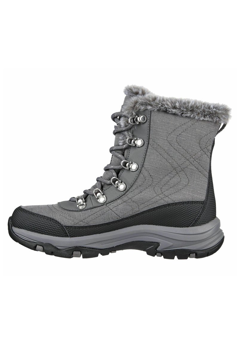 Bota de senderismo gris con parte superior de tela texturada, cuello de piel sintética, ojetes metálicos y suela de goma negra con dibujo de tracción.