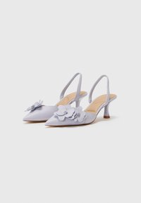 Talons slingback lilas avec bout pointu, détails en appliqué floral et un petit talon épuré. Texture satin lisse et design minimaliste.