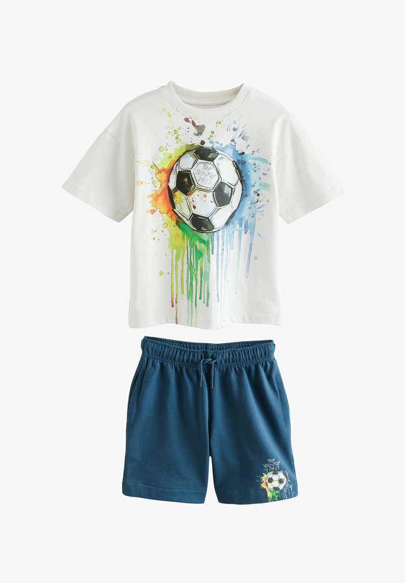 T-shirt bianca in cotone con un design a spruzzo colorato e un pallone da calcio in bianco e nero, abbinata a pantaloni corti blu con cordino e grafiche.