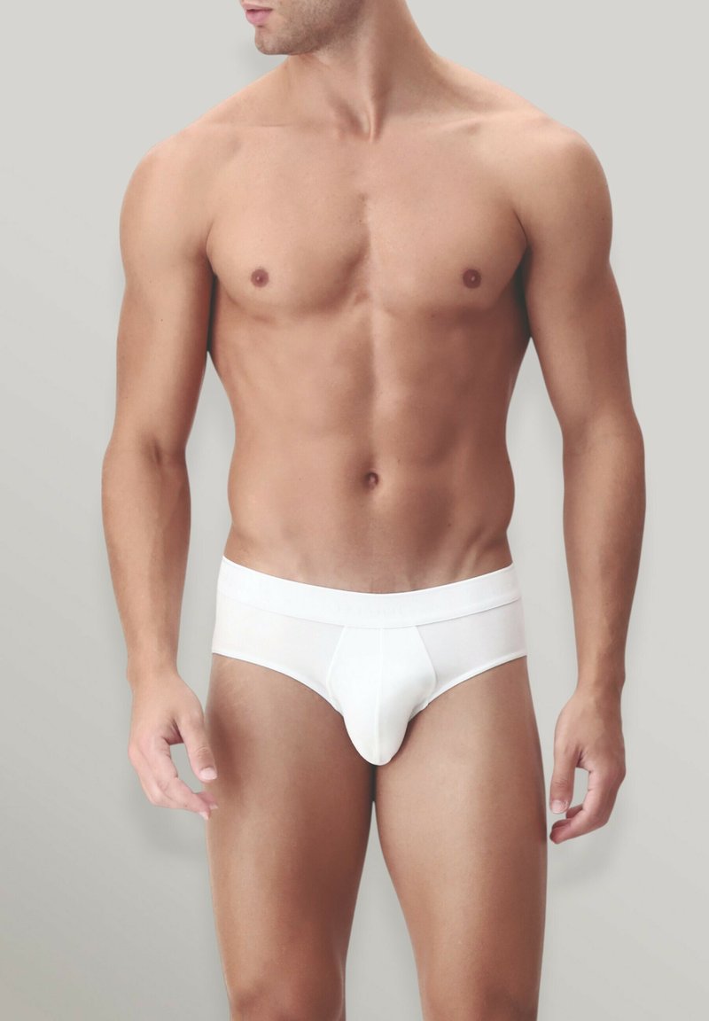 Slip in cotone bianco con una vestibilità aderente, caratterizzati da una fascia elastica comoda e una tasca sagomata. Texture liscia, design minimale e senza motivi.