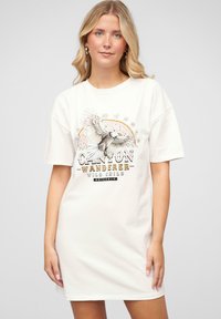 Valge puuvillane t-särgidress, millel on graafiline disain kotkaga, tekst "CANYON WANDERER" ning "WILD CHILD" mustade ja kuldsete tähtedega.