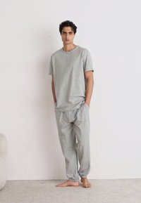 Lichtgrijze katoenen t-shirt en sweatpants set. T-shirt heeft een ronde hals; de broek heeft een elastische tailleband en taps toelopende boorden.