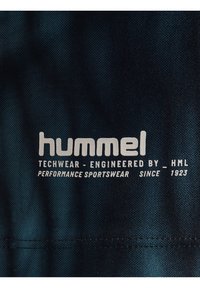 Donkerblauwe sportkledingstof met het "hummel" logo in witte tekst en de slogan "TECHWEAR - ONTWORPEN DOOR - HML".