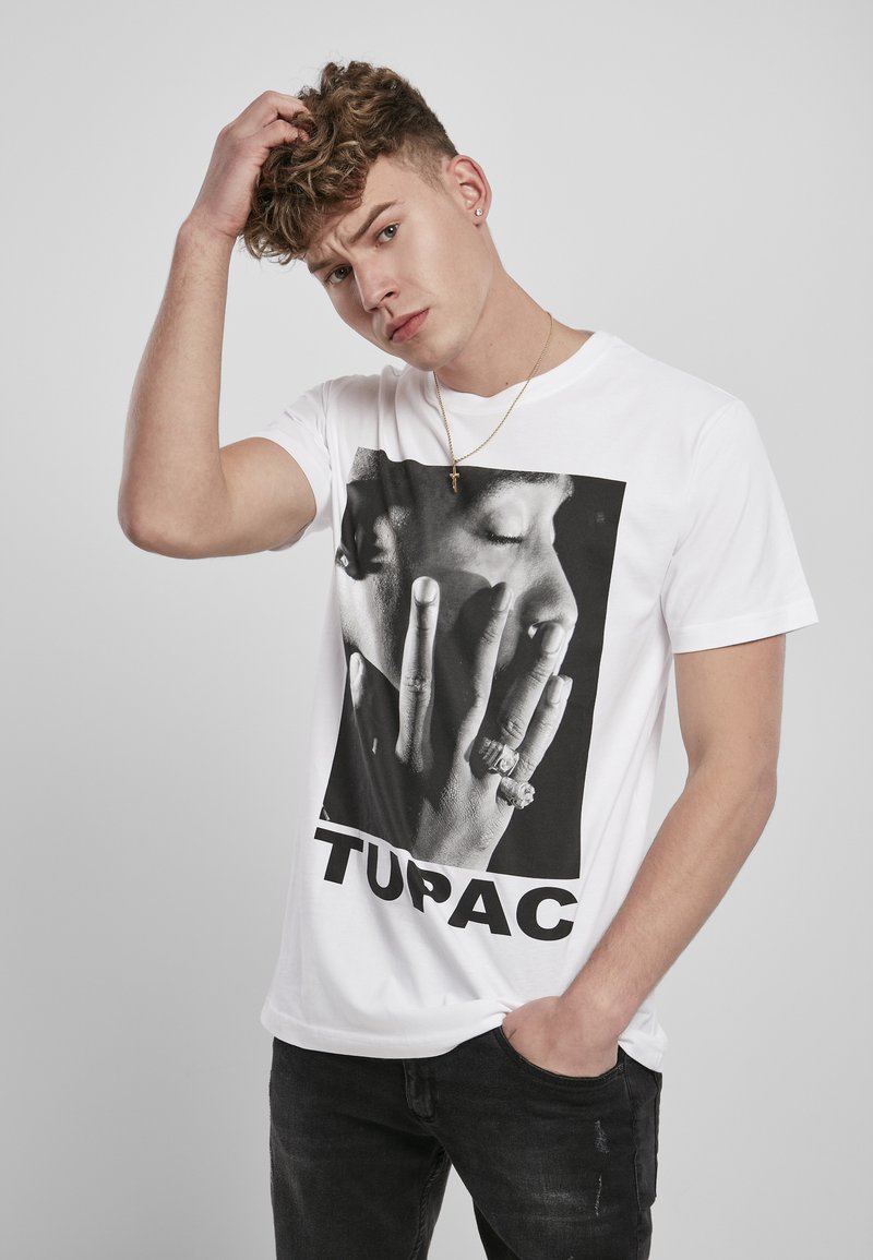 White cotton t-shirt featuring a large black and white graphic of a hand covering a face, text reading "TUPAC" at the bottom.