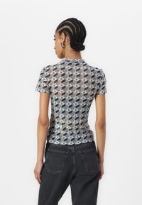 Sheer short-sleeve top featuring a geometric pattern in black and grey. Fitted design with a round neckline and smooth texture.