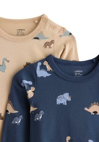 Dvě bavlněné dětské body: jedno béžové s barevnými potisky dinosaurů, druhé tmavě modré se stejnými vzory. Obsahuje patentky na límci.
