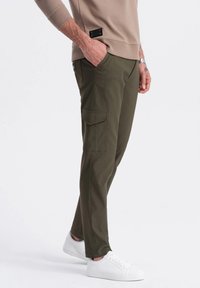 Olivgrön cargobyxor med sidofickor, tillverkade av ett lätt material. Kombineras med vita sneakers. Enkel design, rak passform.