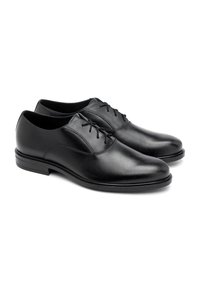 Crne kožne cipele s glatkom teksturom, zaobljenim prstom i minimalnim dizajnom vezanja; imaju blago uzdignutu, elegantnu potplat.