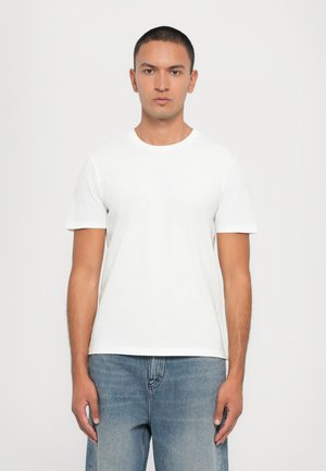 White cotton t-shirt with short sleeves, crew neck, and a classic fit, paired with light blue denim jeans. Solid plain design, no patterns.