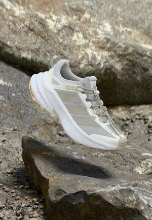 Scarpa da corsa leggera in grigio e bianco, con tomaia in mesh traspirante, dettagli testurizzati e suola in gomma resistente.