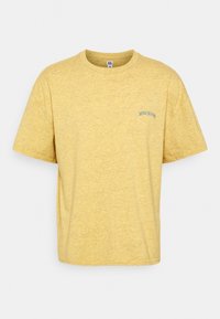 Gul kortärmad t-shirt tillverkad av ett strukturerat tyg. Har en rundad halsringning och diskret blå brodyr av "BDG JEANS" på vänster bröst.