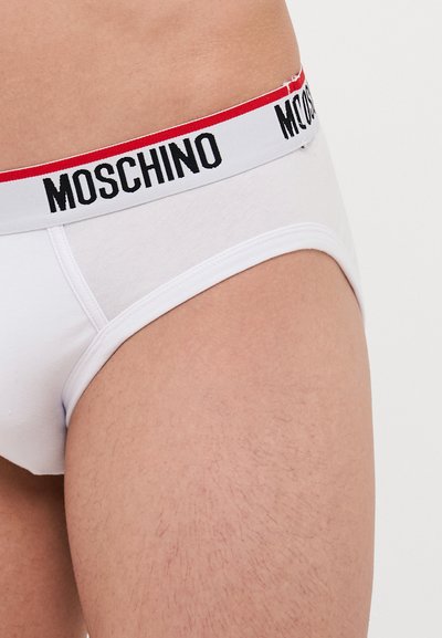 Fehér pamut alsónadrág fekete és piros rugalmas derékrésszel, amelyen a "Moschino" logó található. A dizájn testhez simuló és sima textúrájú.