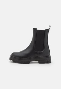 Black leather ankle boot with elastic side panels, rounded toe, and textured rubber sole. Features a loop at the back for easy wear.