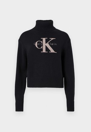 Marineblauwe crop trui met een geribbelde turtleneck, voorzien van een lichtroze geborduurd 'CK' logo en 'calvin klein' tekst. Glad brei-textuur.