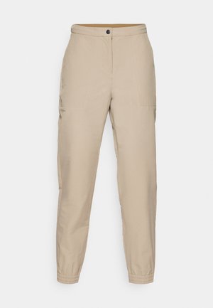 Beige, schmal zulaufende Hosen mit flacher Vorderseite, seitlichen Taschen, elastischen Bündchen und einem Knopfverschluss. Hergestellt aus glattem Stoff mit leichtem Glanz.