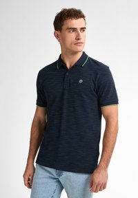 Polo de color marino con detalles verdes y un sutil patrón de rayas. Mangas cortas y un cuello clásico con tres botones. Detalle de logo de goma en el pecho.