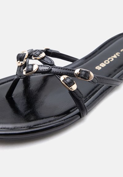 Μαύρο δερμάτινο σανδάλι με πολλαπλούς λεπτούς ιμάντες που διαθέτουν μικρές χρυσές αγκράφες, χοντρή σόλα και εμφανές όνομα μάρκας στην εσωτερική σόλα.