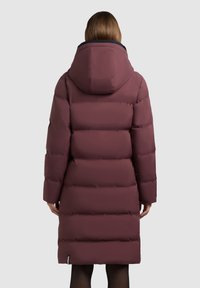 Burgundi punane kapuutsiga sulejope, millel on tikitud disain ja keskmise pikkusega lõige. Sile tekstuur ja mustad sisemised aktsendid.