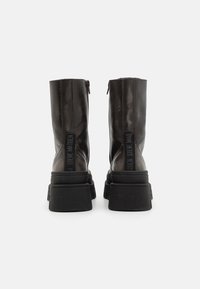 Black leather ankle boots with a chunky sole, featuring a back zipper closure and embossed logo on the heel and sides.