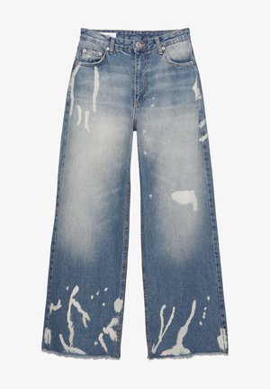 Light blue wide-leg jeans made of denim. Features distressed areas and splattered white accents. Raw hem at the bottom. Classically styled pockets.