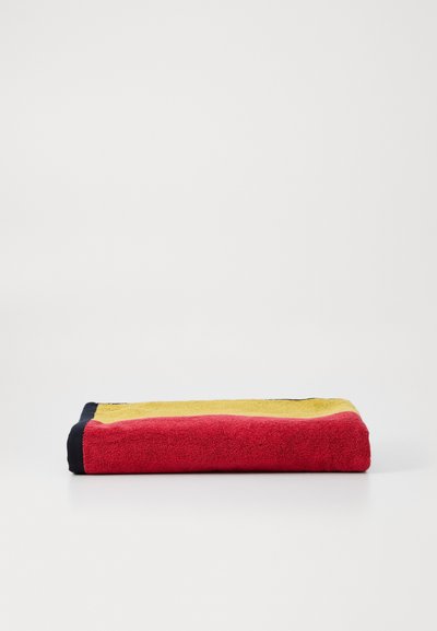 Cotton towel featuring horizontal stripes in red, yellow, and blue. Soft texture with a plush feel. Folded and displayed on a white surface.