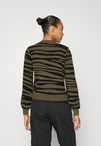 Pull vert et noir à rayures avec un motif texturé, des poignets et un ourlet côtelés. La coupe est ajustée, avec un col rond et des manches longues.