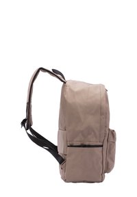 Sac à dos beige avec une finition texturée, doté de sangles noires réglables, d'une poche avant et d'un dos rembourré pour plus de confort.