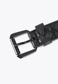 Czarny skórzany pasek z pikowanym wzorem, z błyszczącą czarną metalową klamrą i uchwytem na pasek. Akcentowany detalem z logo na skórze.