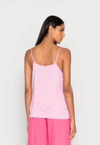 Camisola de alças fina, em rosa claro, com tecido suave e respirável e um corte descontraído. A parte de trás exibe um detalhe de costura simples.