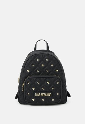 Sac à dos noir matelassé Love Moschino avec des clous dorés en forme de cœur, d'étoile et de cercle, et une poche avant zippée sur fond blanc.