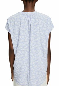 Hellblaues Blusenshirt mit kurzen Ärmeln, floralem Muster, weicher Textur, Falten am Ausschnitt und abgerundetem Saum.