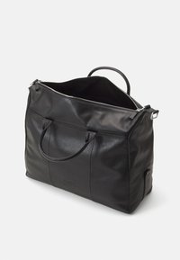 Black leather duffel bag with dual handles, zip closure, large interior, smooth texture, and a subtle logo on the front.