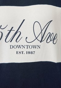Marinblå och vitrandig t-shirt i texturerad bomull, med texten "5th Ave DOWNTOWN EST. 1987" i kontrasterande typografi.