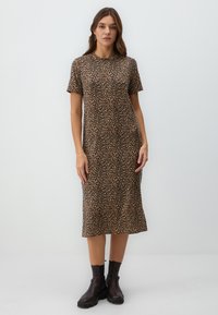 Leopardenmuster-Kleid in Braun und Schwarz, mit kurzen Ärmeln, knielang, aus weichem Stoff, kombiniert mit schwarzen Stiefeletten.