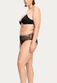 Ensemble de lingerie en dentelle noire composé d'un bralette triangle avec des bretelles fines et d'une culotte taille haute assortie, mettant en valeur des motifs floraux complexes.