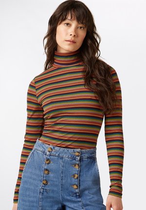 T-shirt à manches longues et col roulé avec un motif rayé multicolore en rouge, vert et jaune. Assorti à un short en denim bleu taille haute avec des boutons à l'avant.