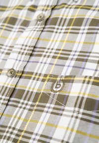 Kariertes Hemd in Olivgrün, Weiß und Gelb. Verfügt über braune Knöpfe, dezente Stickerei eines Buchstabens 'b' und ein strukturiertes Baumwollgewebe.