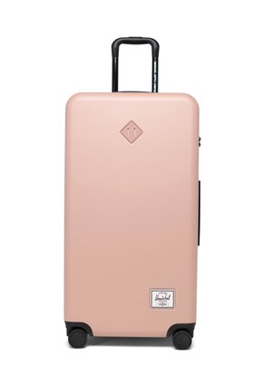 Hard-shell suitcase in soft pink with black accents, retractable handle, four black wheels, and a front logo label. Large and rectangular design.