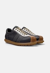 Black leather shoes with beige accents, designed with a rounded toe, brown rubber sole, and contrasting white lace detailing.