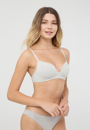 Bralette in cotone grigio chiaro con scollatura profonda, spalline sottili e design senza cuciture. Texture morbida e stile minimalista.