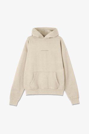 Haut à capuche beige avec une poche avant, des poignets côtelés et un ourlet côtelé. Présente un logo en relief subtil au centre. Tissu doux et texturé.