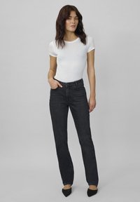 Högmidjade svarta jeans i denim, med en rak bendesign, subtil sömnad och framfickor, i kombination med en åtsittande vit skjorta.