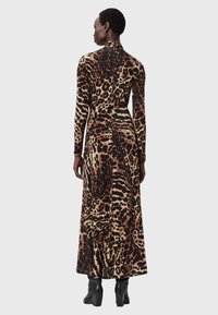 Langærmet, tætsiddende kjole i leopardmønster med nuancer af brunt og sort. Den har en høj halsudskæring og en slank, flodende silhuet.