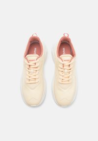 Beige leather sneakers with a textured finish, lace-up design, white soles, and pink accents on the tongue and around the collar.