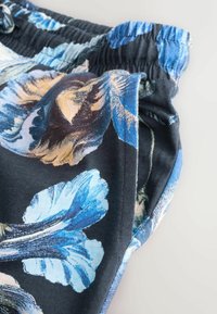 Szorty w kwiatowy wzór z czarnym tłem, niebieskimi i beżowymi kwiatami, z miękkiego materiału i elastyczną talią dla wygody.