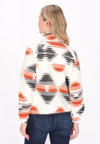 Pullover in pile bianco con motivi geometrici arancioni e grigi; presenta un colletto, maniche lunghe e una vestibilità comoda.