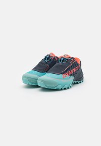 Trailrunning sko med svart overdel, turkise såler og oransje detaljer. Har strukturert grep og hurtiglåsesystem for sikker passform.