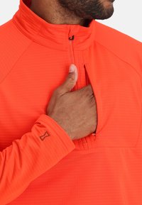 Heldere oranje half-zip pullover van textuurstof, met een hoge kraag en een ritszak op de borst, met logo-details op de mouw.